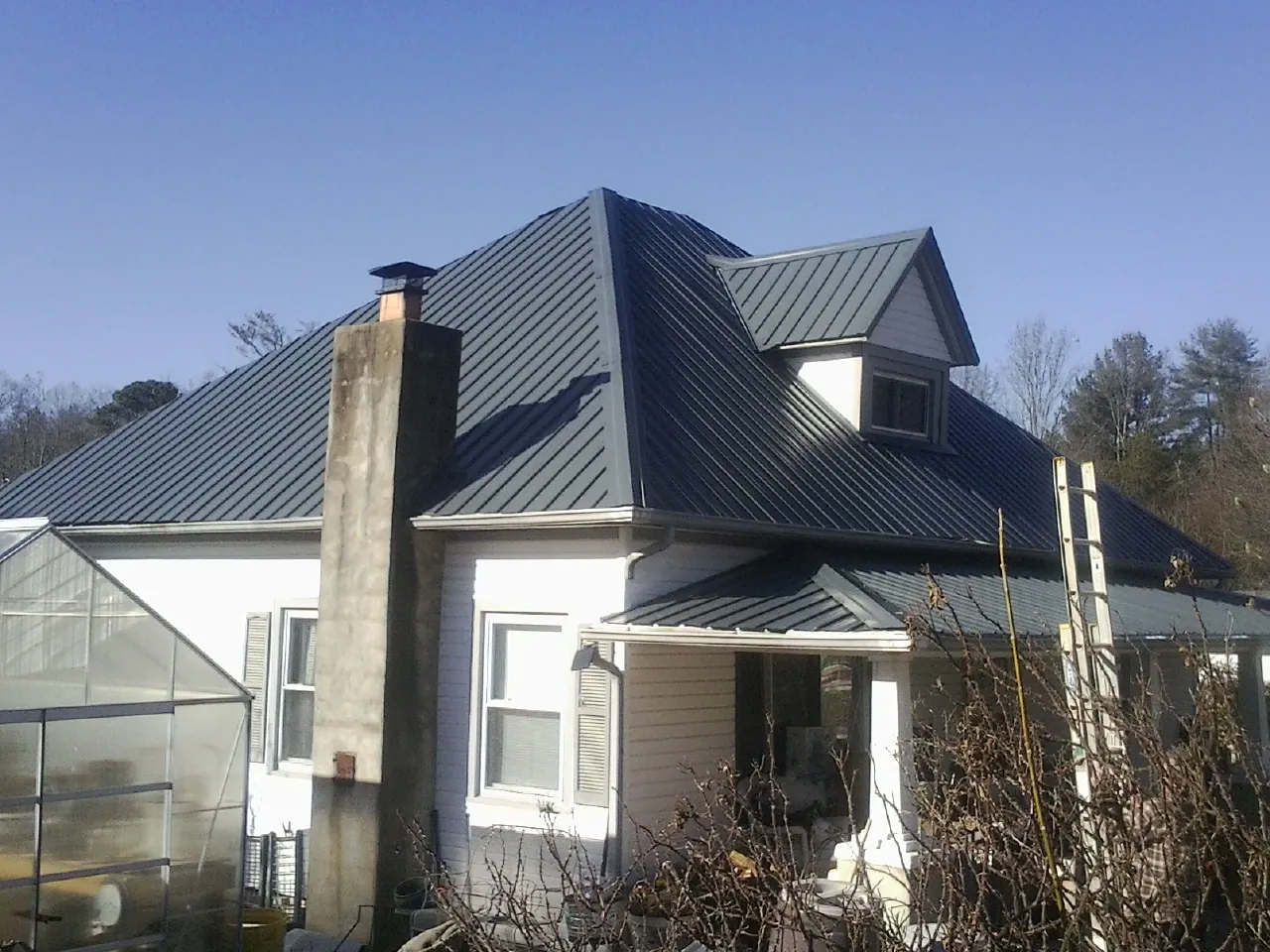 Dark blue standing seam metal roof on a white farmhouse with dormer — Slate & Tile Roof Repair by Roofing Brothers in Naval Air Station Jrb