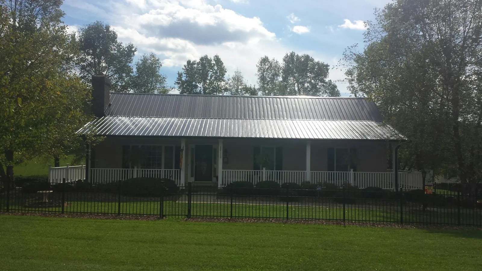 Gray metal roof on a brick ranch with a full width front porch — Gutter Guard Installation work by our crew in Naval Air Station Jrb