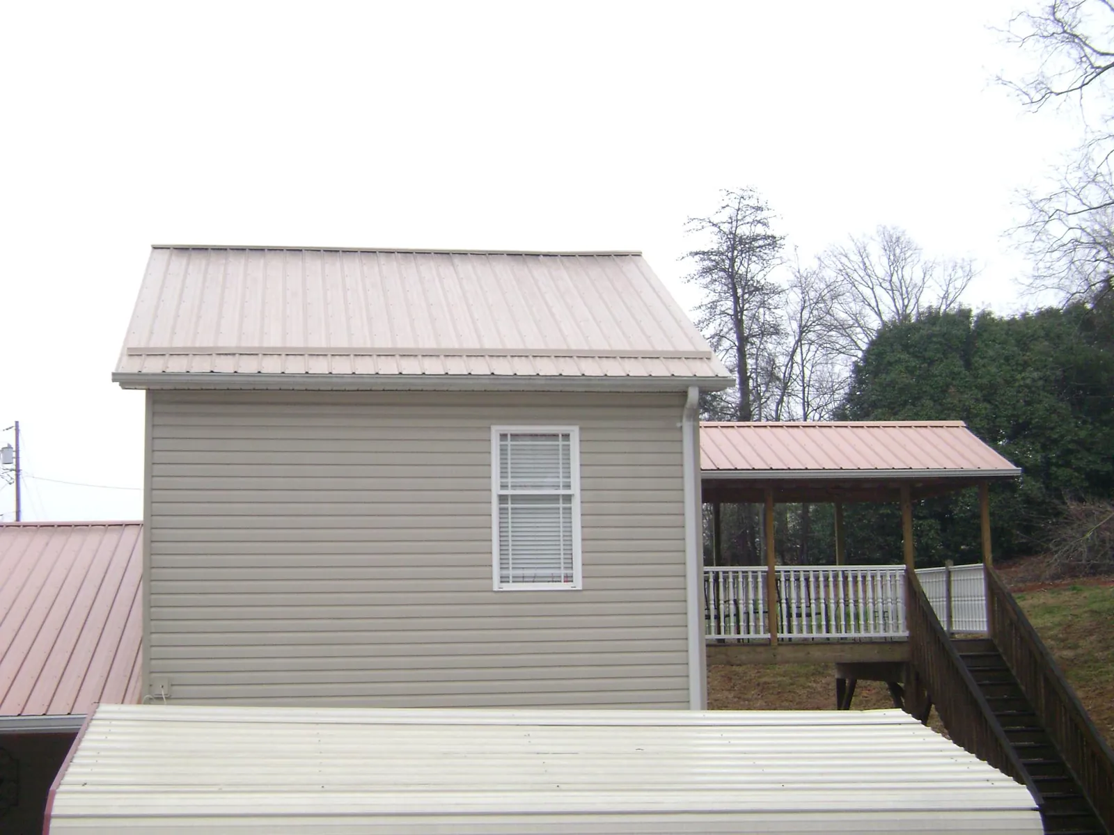 Tan metal roofs on a two story addition and attached porch, from a Roof Replacement job in Naval Air Station Jrb