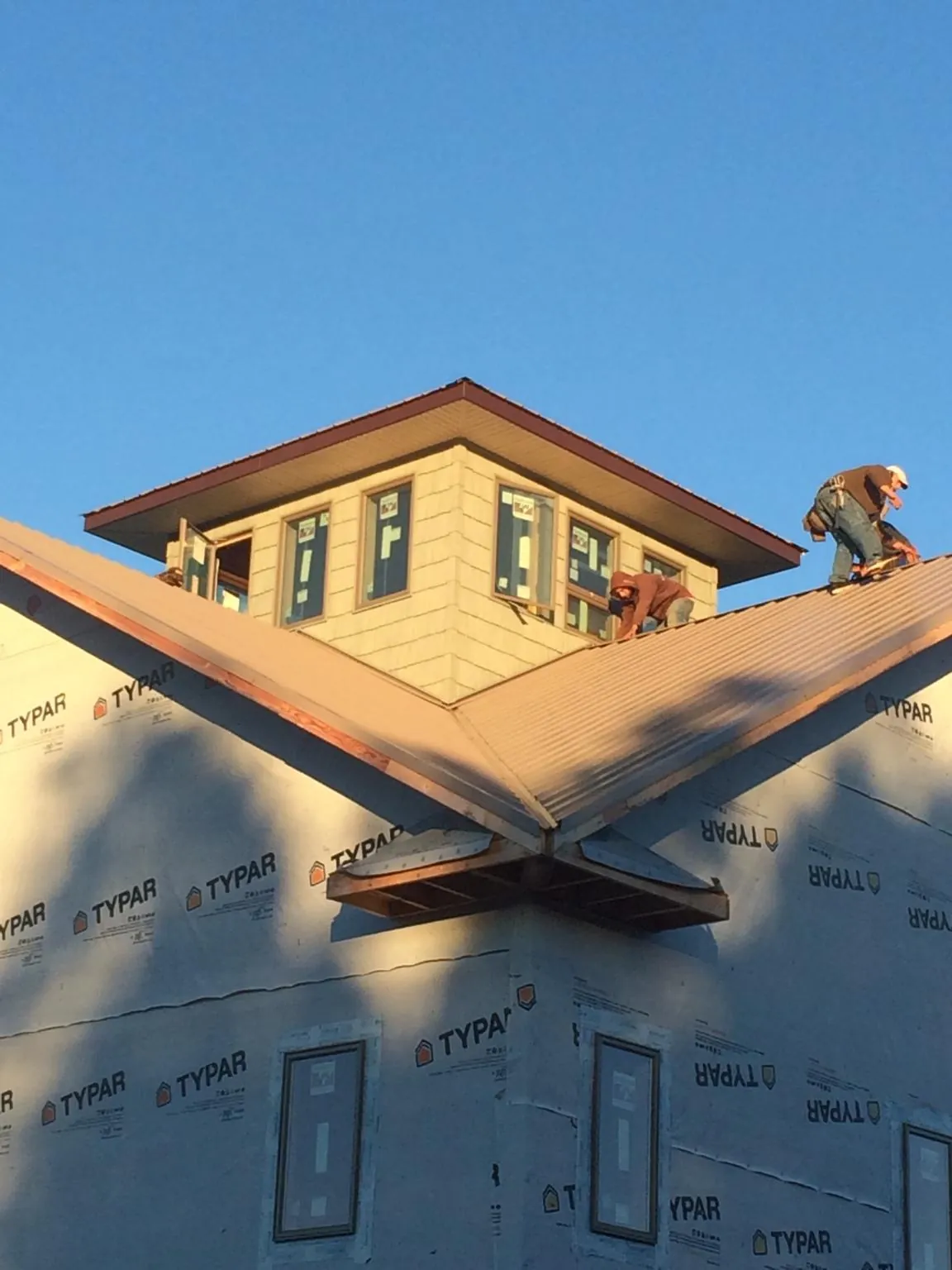 Roofers working around a rooftop cupola on a new metal roof at sunset — Roof Waterproofing in Naval Air Station Jrb by Roofing Brothers